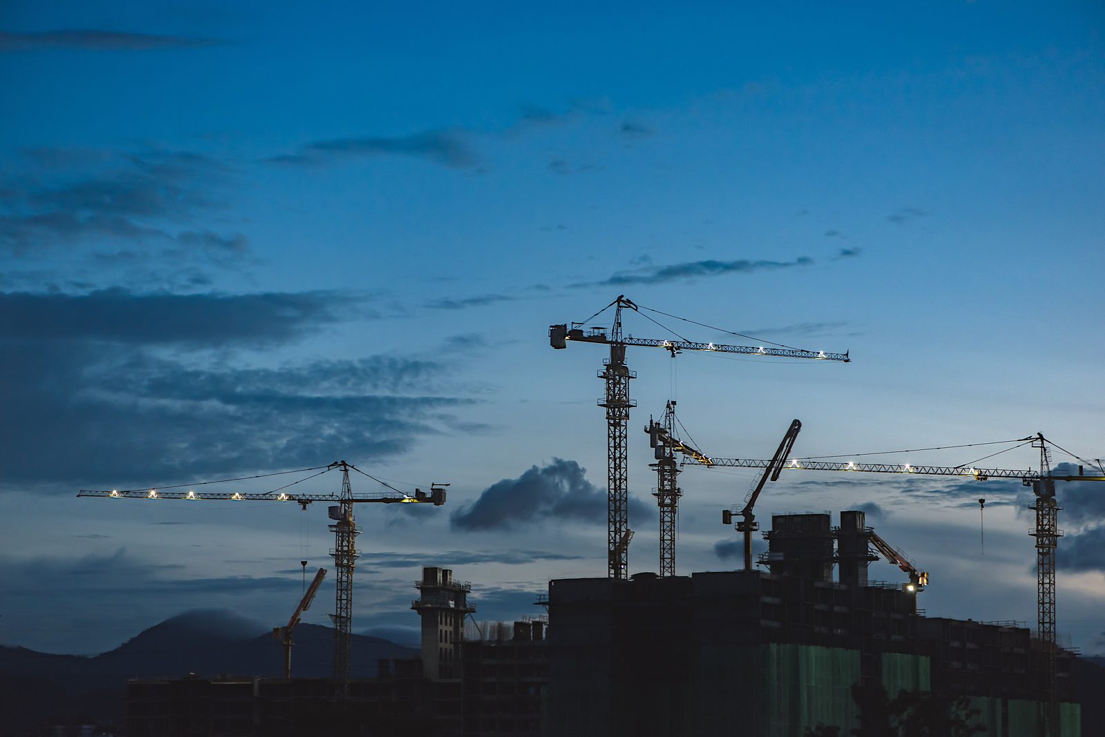 Tower cranes over a construction site at dusk